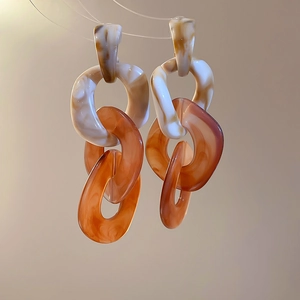 Macro shot of large acrylic chain link earrings with marble and amber resin texture