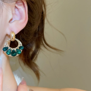 Dettaglio degli orecchini in argento con pietre a goccia verde smeraldo indossati