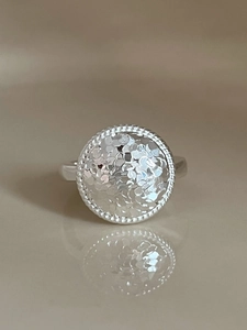 Detailed macro view of silver ring with hammered texture finish and beaded edge design