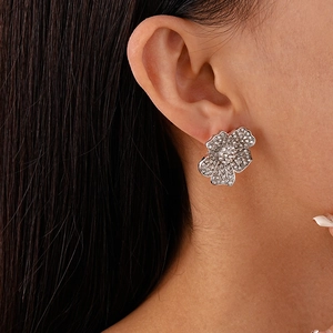 Close-up of model wearing luxury crystal-encrusted flower earrings in silver finish