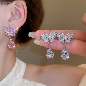 Detail of butterfly drop earrings featuring pink crystals and zircons on a model