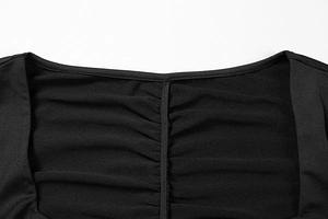Dettaglio dello scollo a V arricciato su abito nero aderente in maglia a trama fine