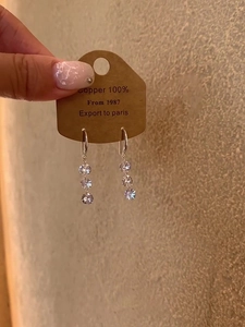 Detailed view of silver hoop earrings with three sparkling round cubic zirconia stones