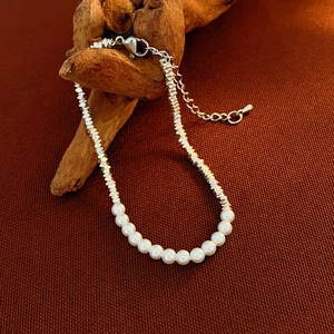 Detail of beaded bracelet featuring white pearls and faceted silver metal beads with lobster clasp