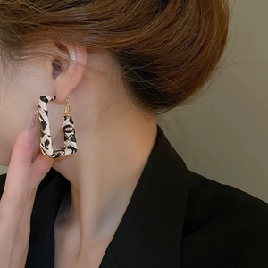 Close-up of leopard print rectangular earrings worn by a model in a retro fashion style