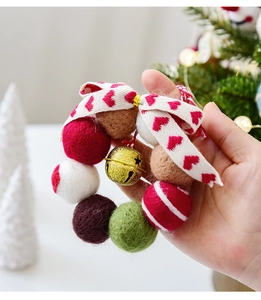 Detail eines Wollfilzkranzes mit goldenem Sternenglöckchen und Herzband für Weihnachten