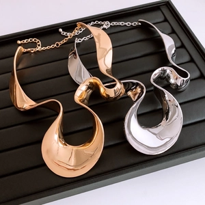 Close-up of gold and silver statement necklaces with wavy metallic texture and lobster clasp