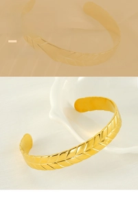 Detail of gold wheat pattern texture on an adjustable C-shaped stainless steel bracelet