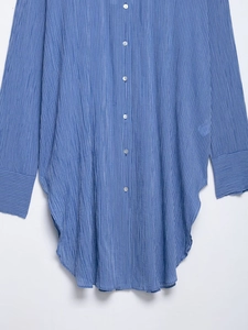 Détail d'une chemise longue à rayures bleues avec boutons nacrés et ourlet arrondi