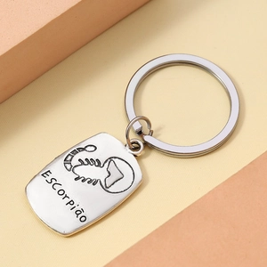 Macro detail of silver alloy Scorpio zodiac keychain with engraved scorpion and text