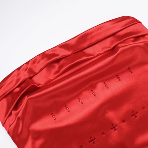 Detailed macro shot of red satin fabric featuring sparkling rhinestones and elegant draping