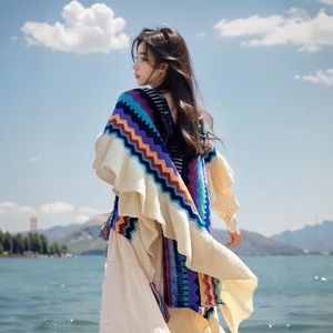 Bohemian knit poncho with colorful stripe patterns and beige fringe ruffles in nature