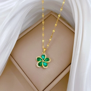 Detailed close-up of a gold necklace featuring a rotating green floral pendant with crystals