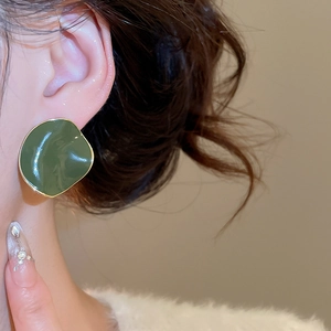 Close-up of model wearing a dark green irregular geometric earring with gold edges