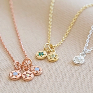 Detailed view of round star pendants in rose gold, gold and silver on soft fabric