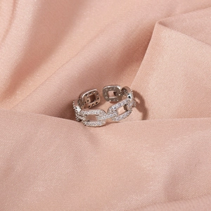 Detail of silver chain ring with pavé cubic zirconia on pink satin fabric background