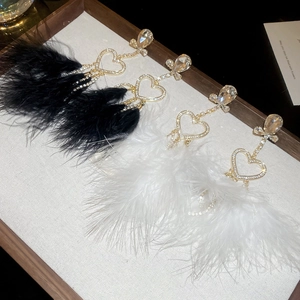 Detailed view of silver heart earrings with rhinestones and long feather fringe pendants