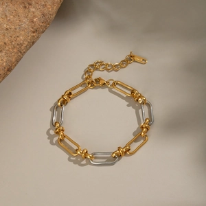 Detail of two-tone gold and silver link chain bracelet with lobster clasp and steel tag