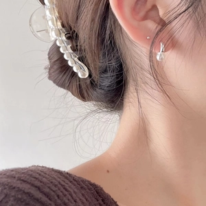 Close-up of pearl embellished hair claw and elegant silver earring on a model
