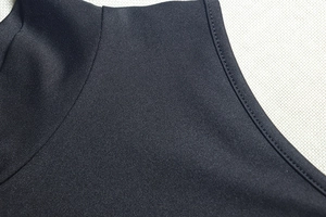 Close-up of black knit fabric showing double-stitched seams and texture on the collar