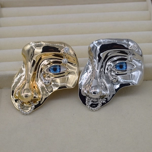 Detail of artistic metal face brooches with blue eyes and chain in gold and silver finish