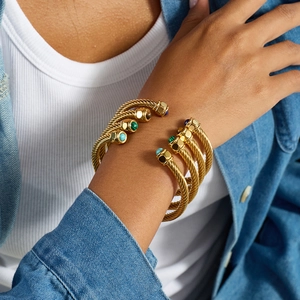 Golden cable cuff bracelet with inlaid green malachite and colorful gemstones on a wrist