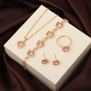 Detail of gold jewelry set with purple heart crystals on a beige display box
