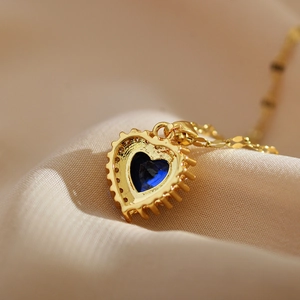Detail of blue heart gemstone pendant with intricate gold setting on silk fabric
