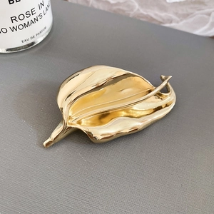 Macro shot of polished gold leaf brooch showing detailed metal texture and realistic veins
