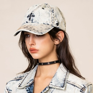 Close-up of light wash denim baseball cap with black cross embroidery and yin-yang patch