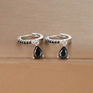 Macro detail of silver drop earrings with pear-cut black zircons and hoop design