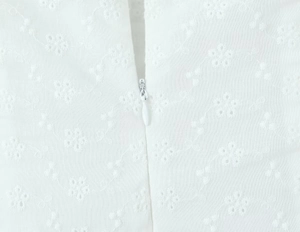Close-up of the invisible zipper and intricate floral lace embroidery on the white dress