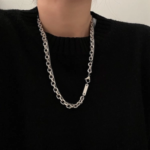 Detail of men's silver double chain necklace with rectangular tag on black sweater