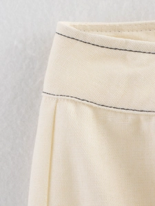 Detalle de los shorts de lino crema con costuras decorativas negras en contraste en cintura