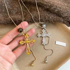 Detail of cross pendants with rhinestones and stones on snake chains in gold and silver