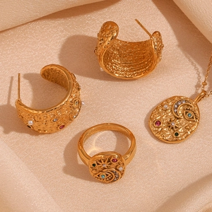 Detail of 18K gold plated jewelry set with celestial motifs on pink satin fabric