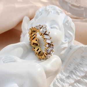 Close-up of gold cubic zirconia ring on an angel statue with elegant beige background
