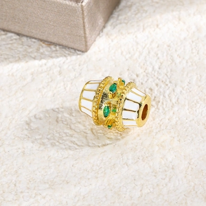 Macro detail of oval gold bead with white enamel stripes and green zircon stones