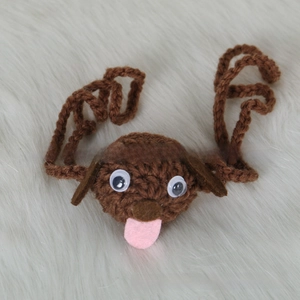 Detail of handmade crochet brown puppy nose warmer with knitted straps and plastic eyes