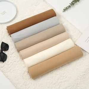 Detail of warm cashmere-feel scarves in earthy tones displayed on soft white fleece fabric