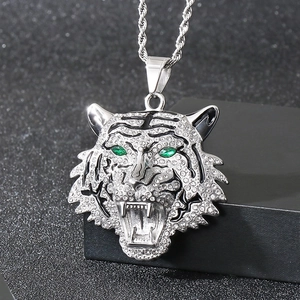 Detail of silver tiger head pendant with inlaid diamonds and green gemstone eyes