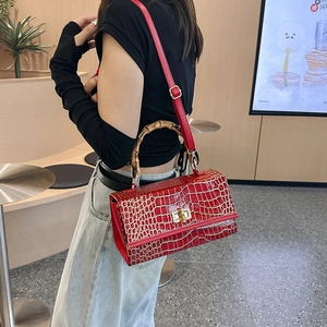 Detailed view of the red crocodile pattern leather bag featuring a bamboo handle and turn-lock