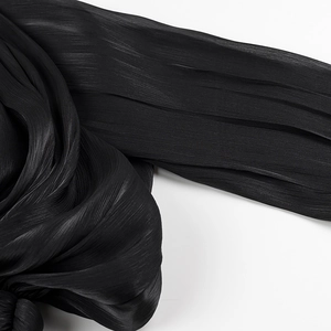 Detailed macro shot of pleated black fabric texture with elegant draping for the dress