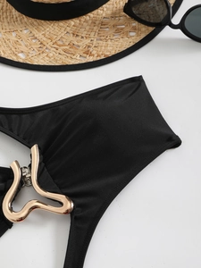 Close-up of golden heart-shaped buckle on black swimwear with beach accessories