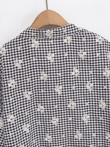 Détail de la broderie florale sur chemise en coton à carreaux noir et blanc avec col