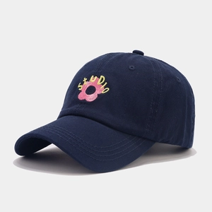 Close-up of pink flower and STUDIO embroidery on a dark blue cotton baseball cap