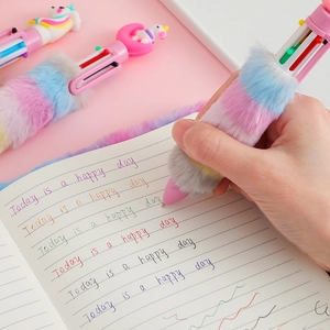 Close-up of cute unicorn plush multi-color ballpoint pen writing on paper