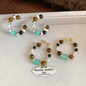 Detail of retro beaded hoop earrings with tiger eye stone, pearl and cat eye stone