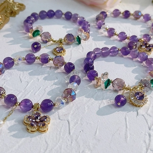 Detailed shot of amethyst bracelets featuring gold flower charms and zircon accents