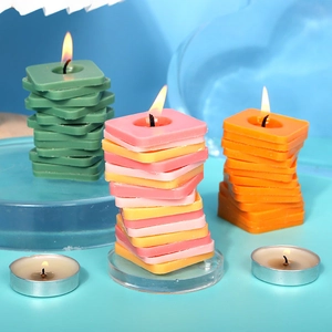 Tres velas geométricas cuadradas de colores y velas de té en una decoración moderna